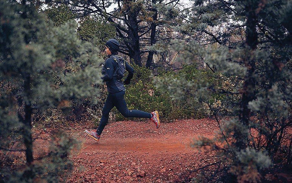 Woman running on a dirt trail in the woods.