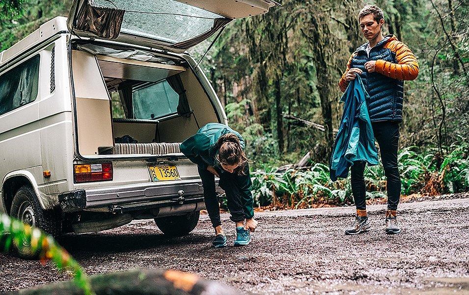 Two people next to a van getting ready for the outdoors. 