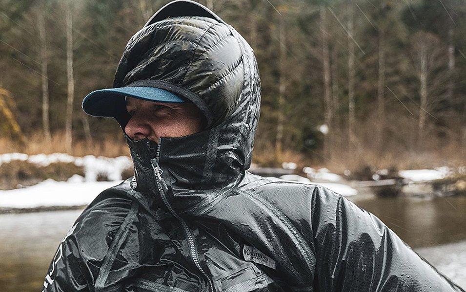 Pro angler Curtis Ciszek stands in front of a snowy river bank looking off in the distance. 