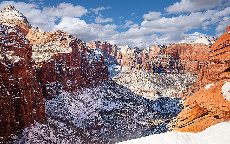 Snow speckles beautiful rust-colored rocks that tower in the distance in Zion National Park.