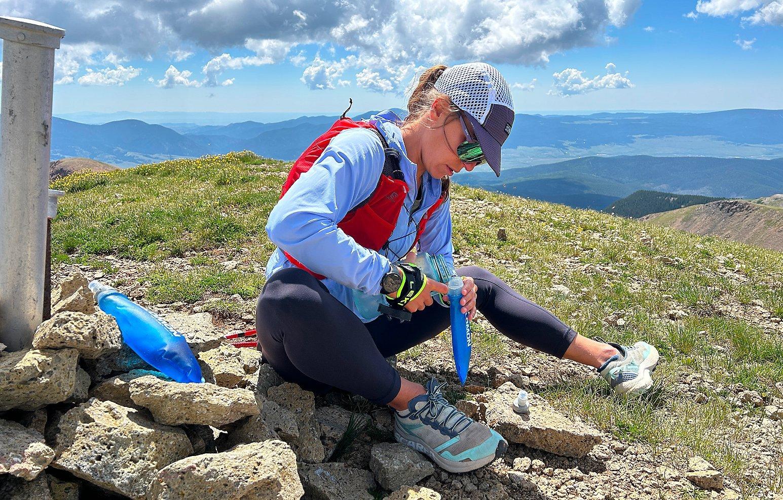 Shayna stops to refill water on a trail run in the mountains.