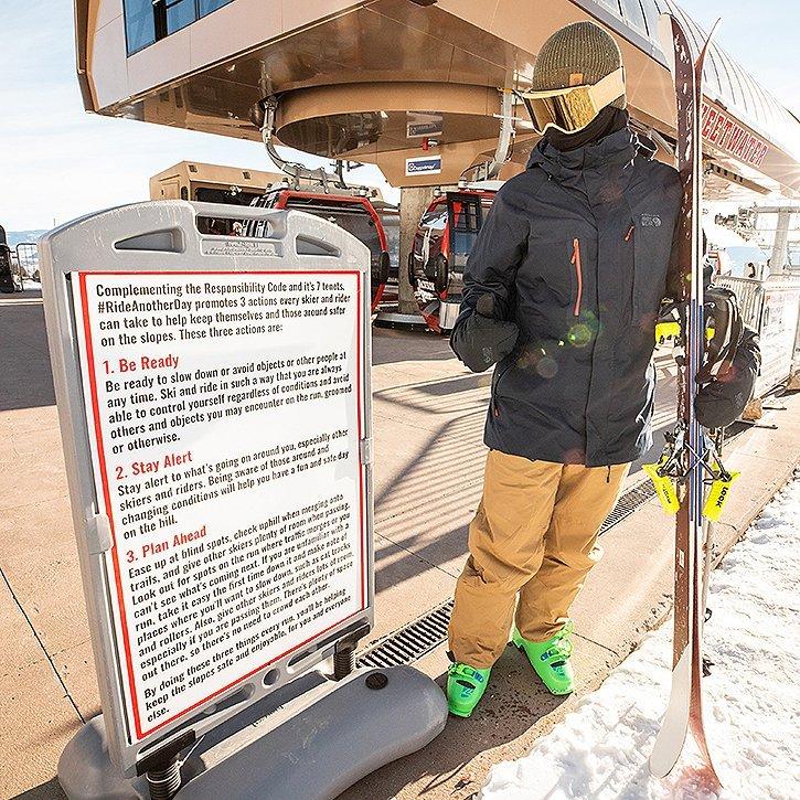 Reading the guidelines posted near the bottom of the chairlift at a ski resort
