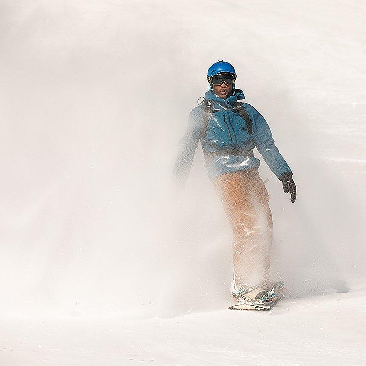 Close up of a snowboarder in very snow conditions making his way down the run