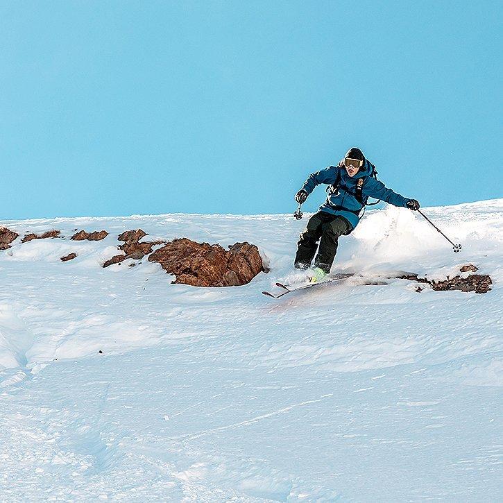 A skier jumps over some rocks on a rough sidecountry run