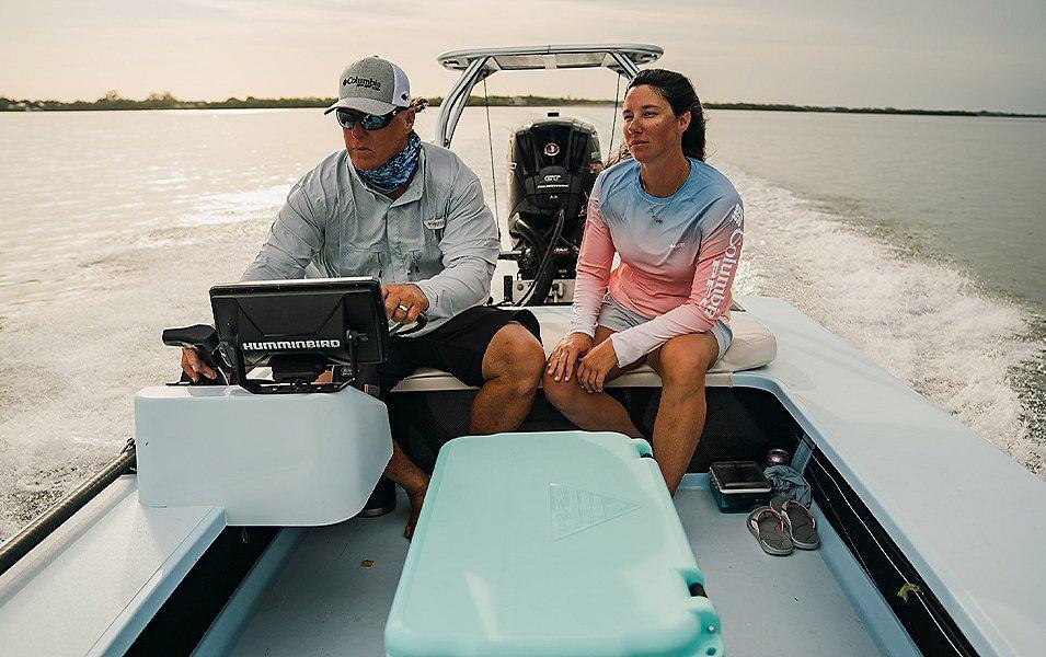 Two people on a boat on the water in late afternoon. 