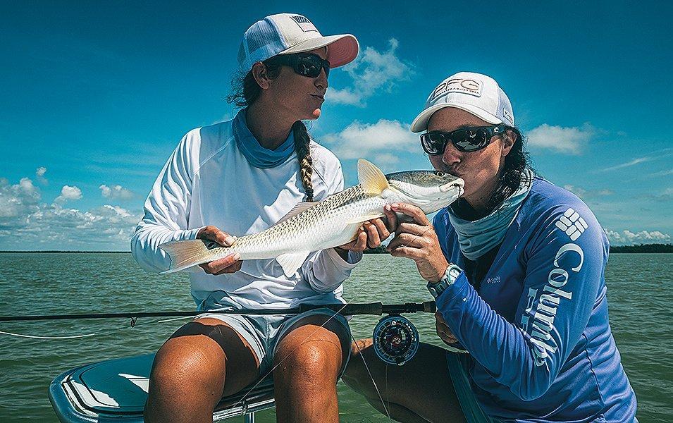 Two women holding a recently caught fish. 