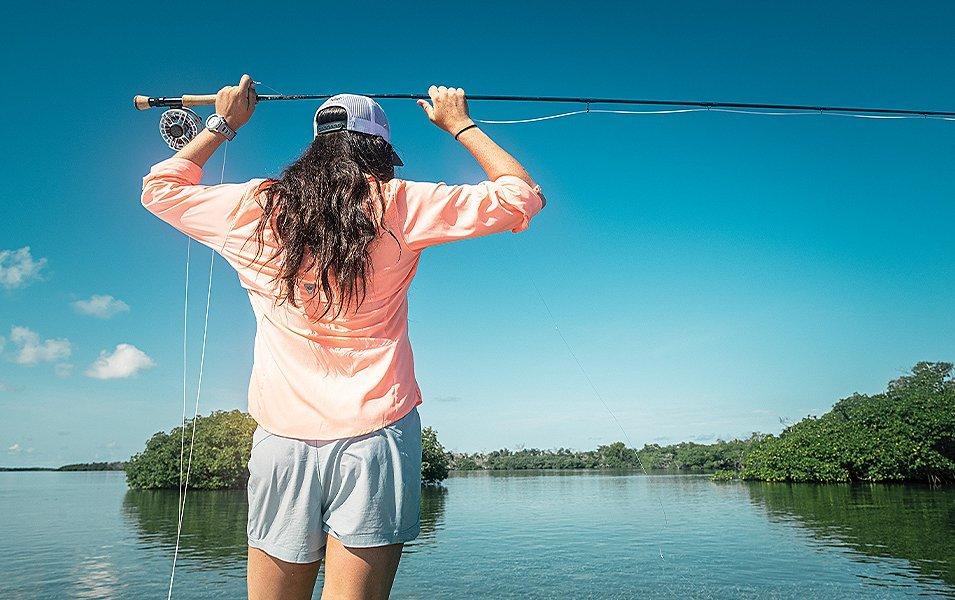 Wesley Locke standing with a fishing reel over her head. 