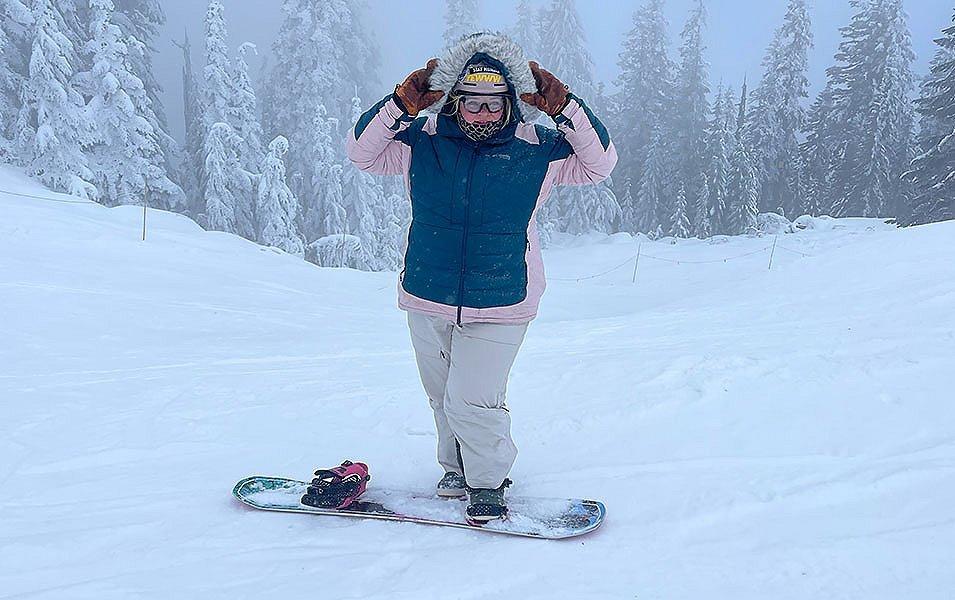 Snoqualmie ski patroller Annet Sootgrabs the hood of her pink and blue Columbia Sportswear jacket as she looks off camera smiling. 