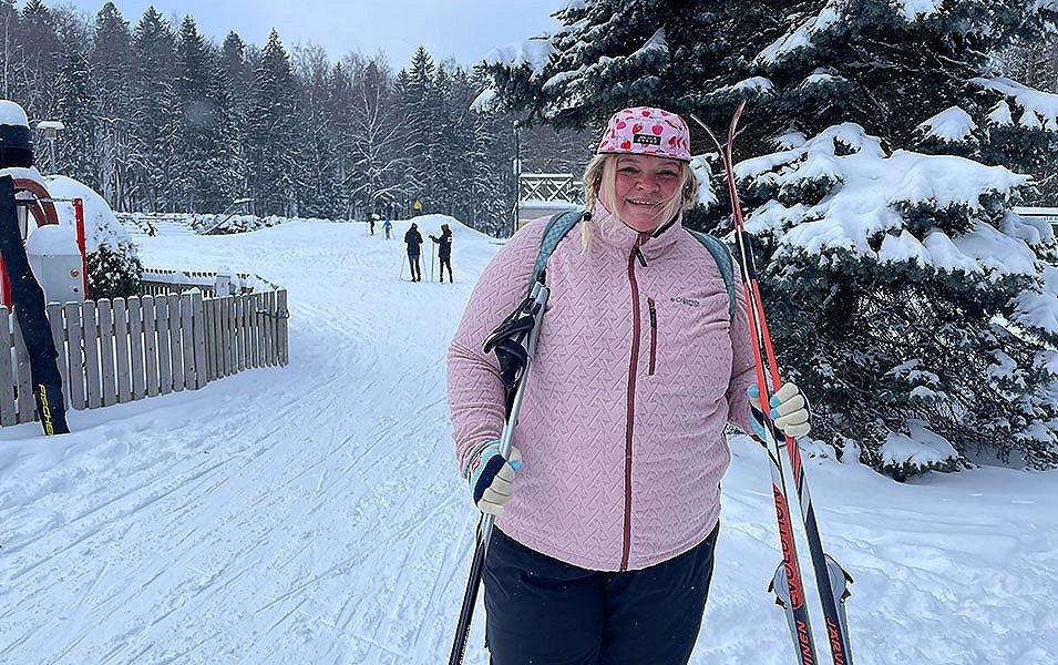 Snoqualmie ski patroller Annet Soot stands near the base area holding a pair of skis and wearing a pink Columbia Sportswear fleece.
