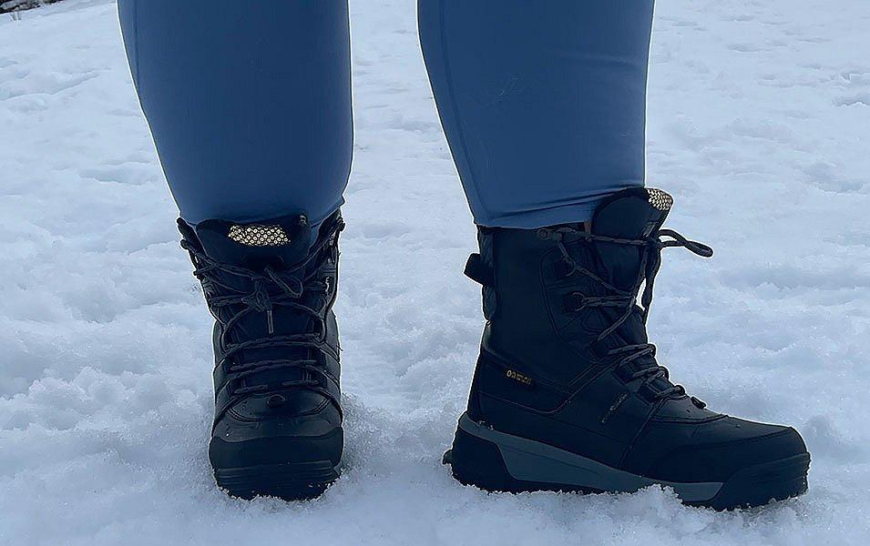 A close-up shot of a pair of black Columbia Sportswear winter boots standing in the snow.  