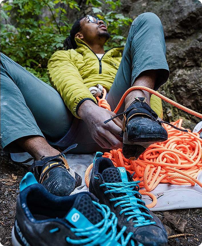 Caleb putting on his climbing shoes, looking up