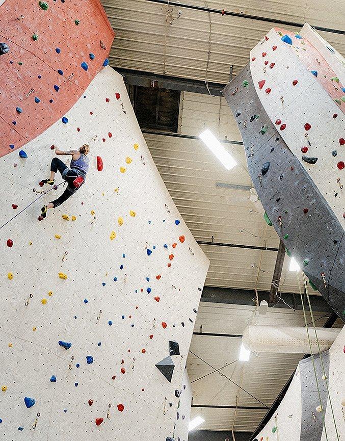 Kyra Condie bouldering in her home climbing gym in Minneapolis, making good progress on the route, with her personal mantra, "you suck try harder" on the wall in the background.