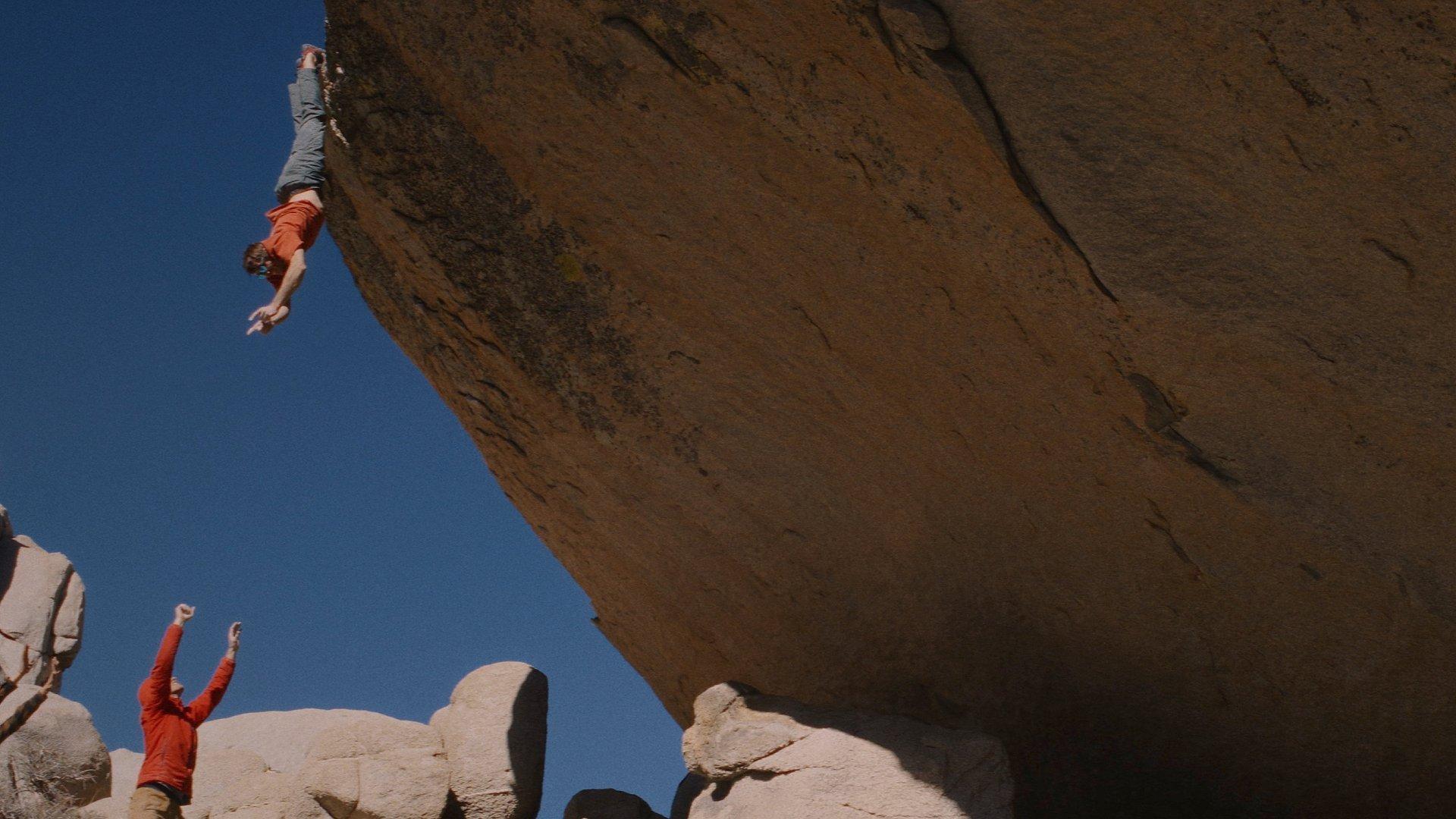 MHW Athlete Ethan Pringle hangs and waves to his fellow climbers while bouldering in the desert.