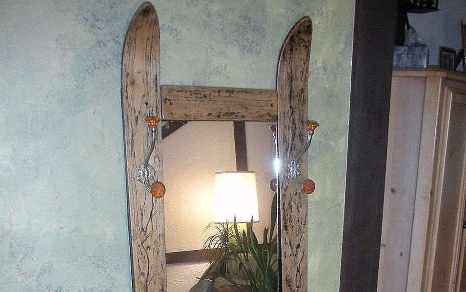 A mirror sits on a wall made with old skis as the frame. 