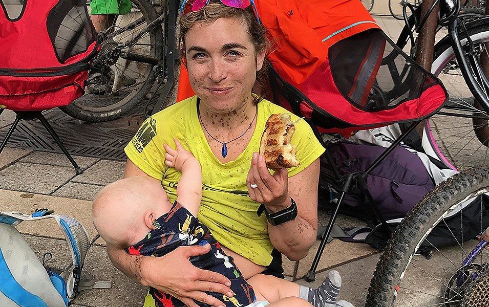 Chelsey Magness breastfeeding and holding a sandwich.
