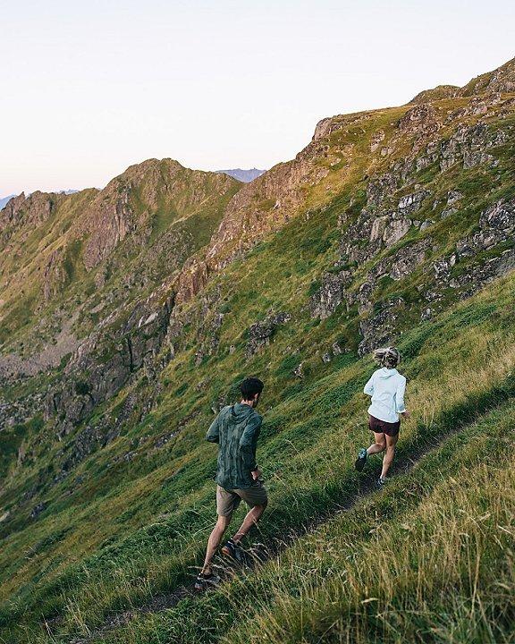Two trail runners running in a lush hillside.
