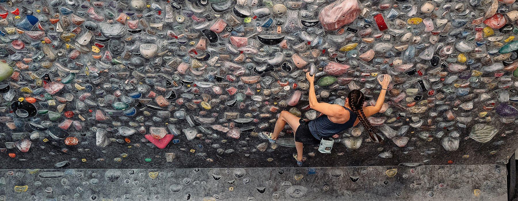 Kyra Condie climbing on a bouldering problem in a climbing gym.
