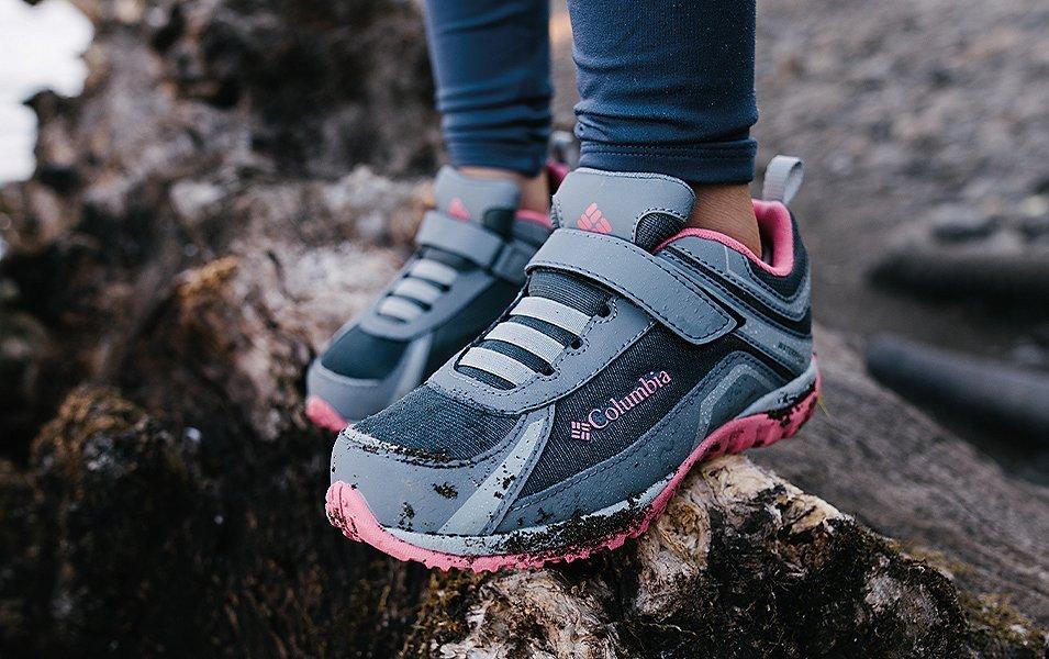 Close up of kids' feet standing on rock.