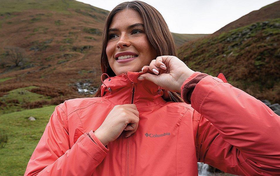 Femme enfilant une veste de pluie rose Columbia.