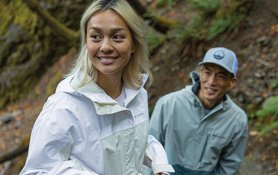 Deux personnes dans une forêt portant des vestes de pluie Columbia Sportswear.