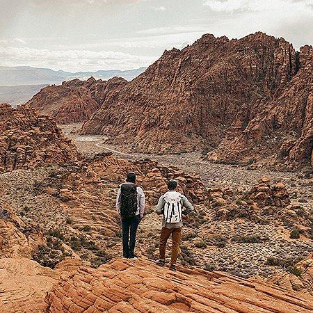 Two hikers look out to the vast landscape of the Utah desert