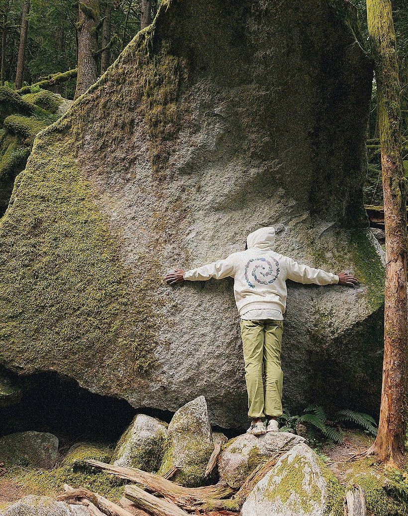 Hugging a mossy rock in a Leave No Trace Extra Vitamins Mountain Hardwear hoody.