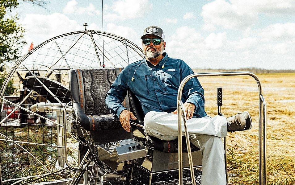 Man sitting on a boat in a marsh. 
