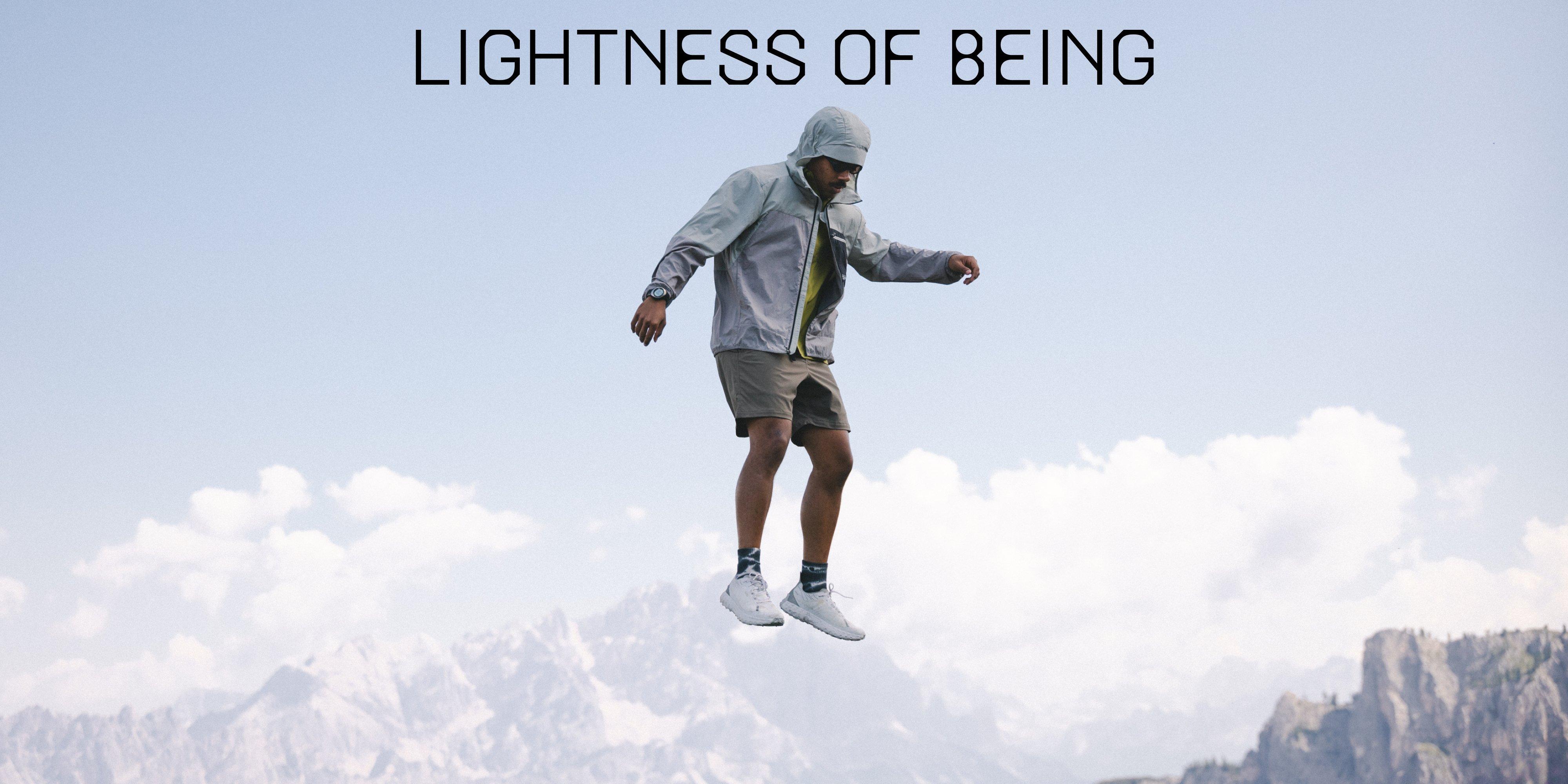 A man in a Wind Veil™ Hooded Jacket and Peak Rambler™ Shorts floats weightlessly, as though frozen in air, in front of a rocky range.