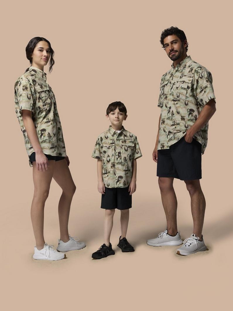 Three people wearing matching safari-print short-sleeve shirts with black shorts and sneakers.