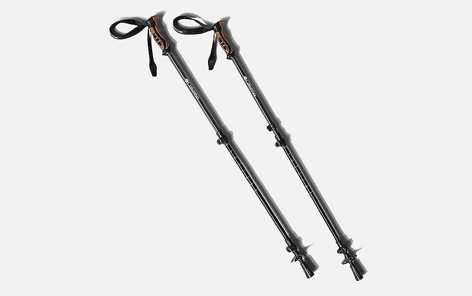 A product image of a pair of black Columbia Sportswear trekking poles with light brown handles set against a white background. 
