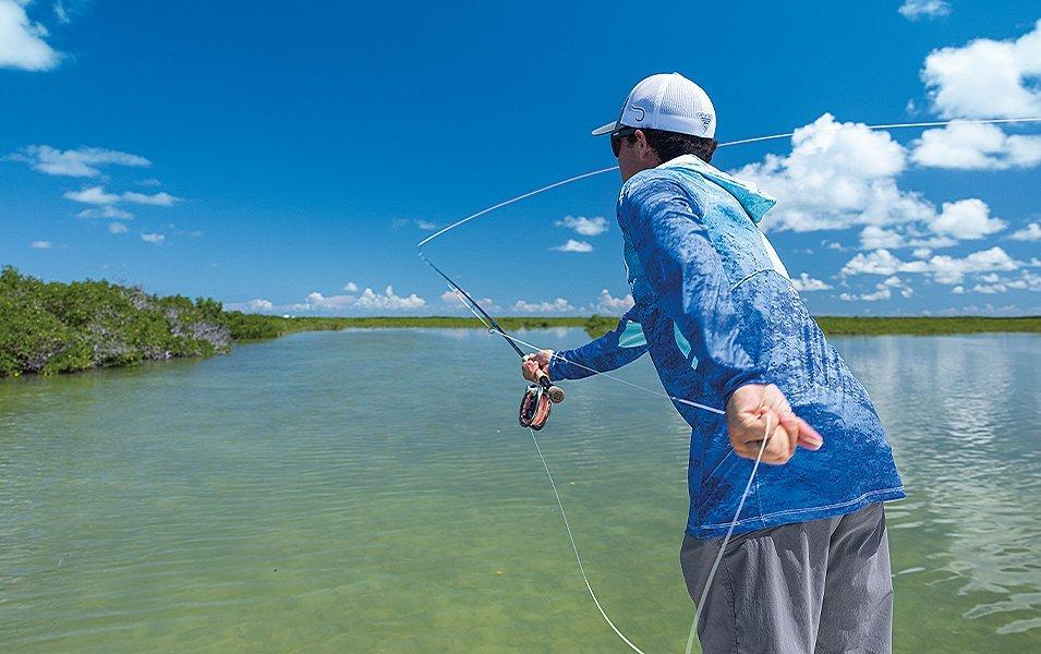 An angler casts a line into the ocean on a beautiful sunny day.