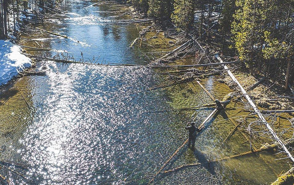 An aerial photo of a man in a river fly fishing from a distance. 