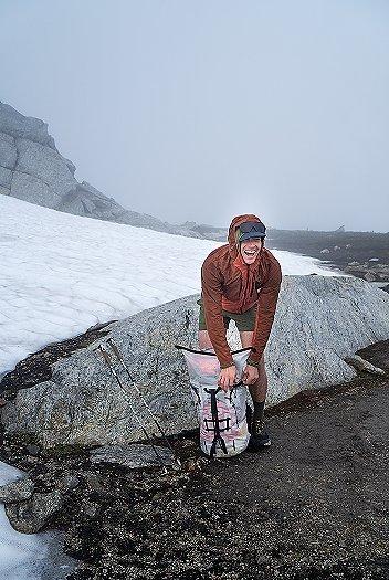 CJ smiling with his backpack with a snowy mountain landscape in the background.