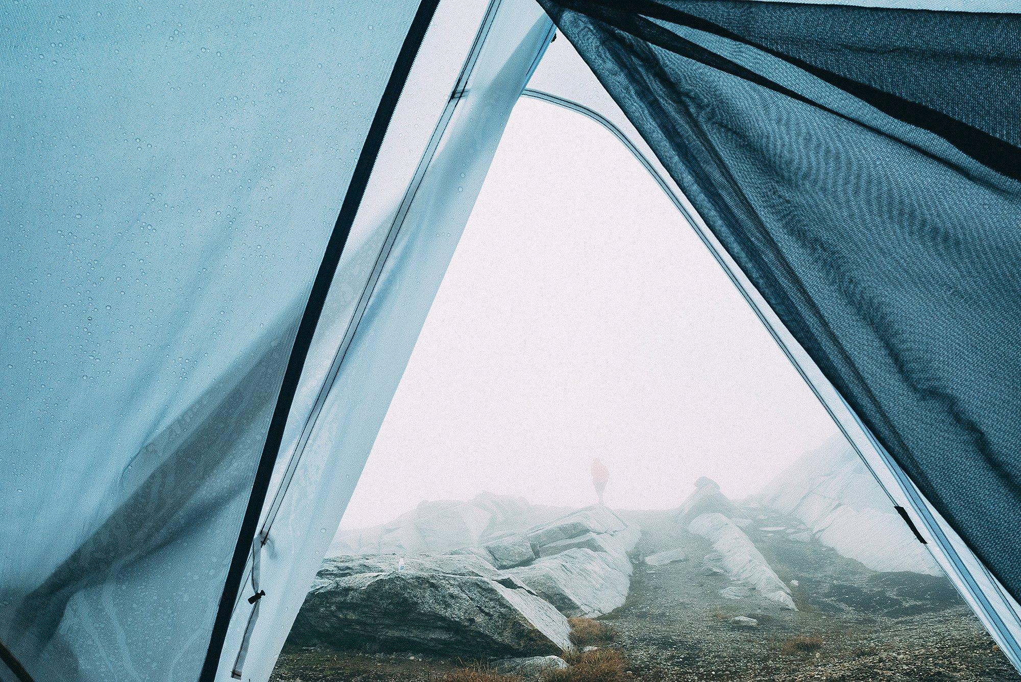 Looking out from the tent on foggy rainy mountain terrain.