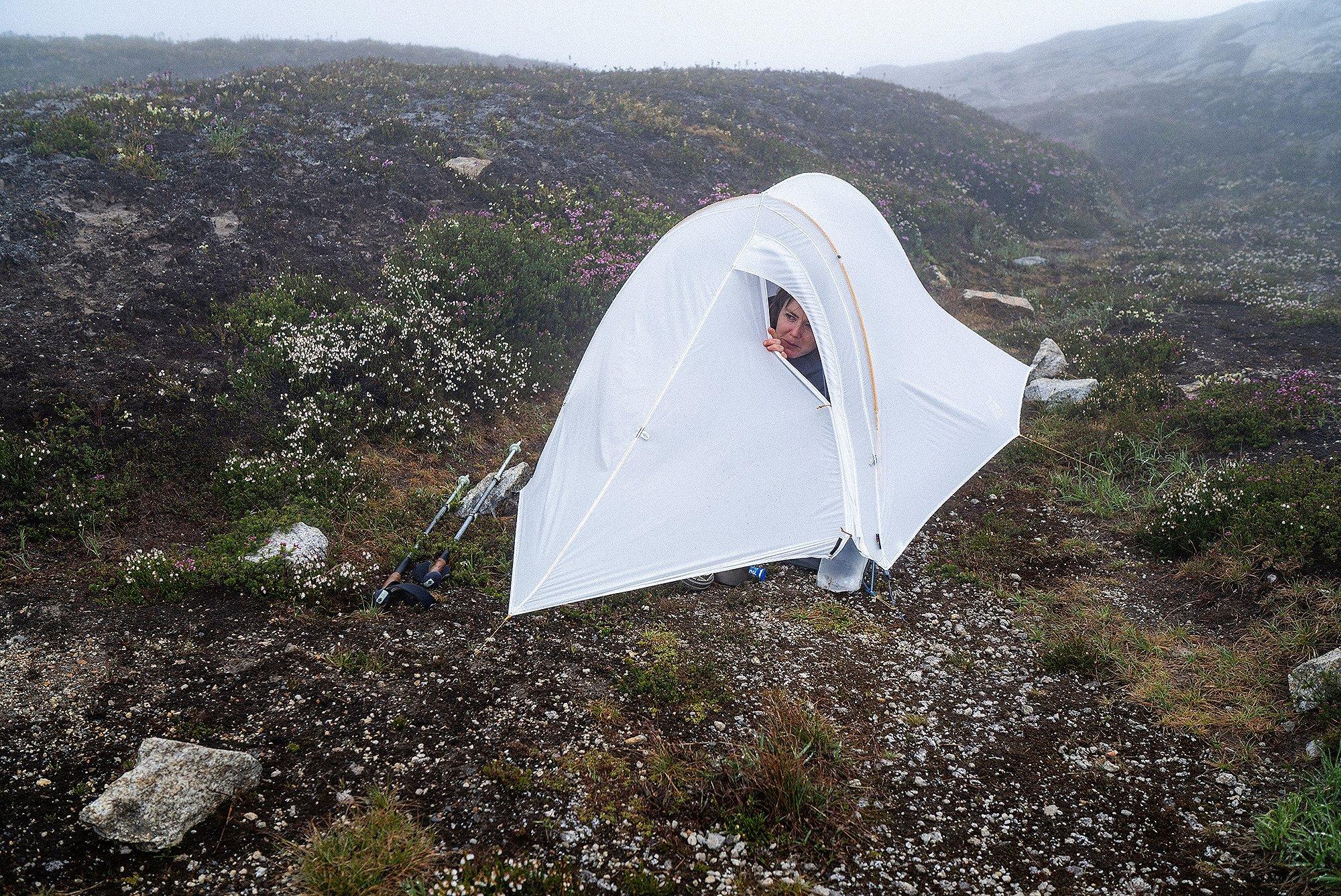 Hannah peeks out of a tent to see if it's still raining or not.