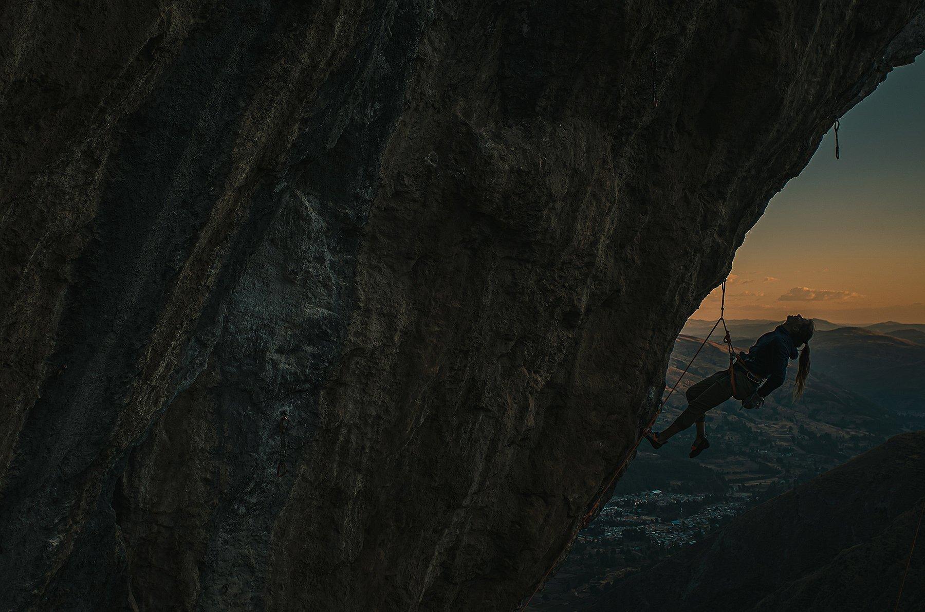 Climbing at dawn in Peru, Charlotte looks up at the rock wall above for her next move.