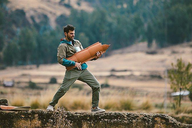 Josh stroking a piece of scrap metal as if it's a guitar close to camp