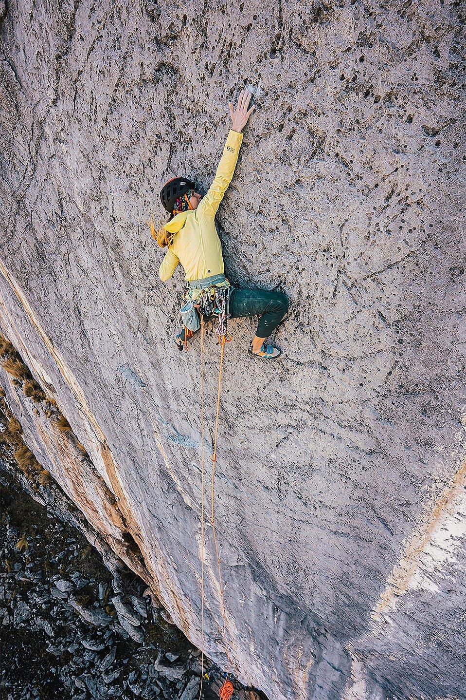 Charlotte working her way up the climbing route wearing the Kor Preshell hoody.
