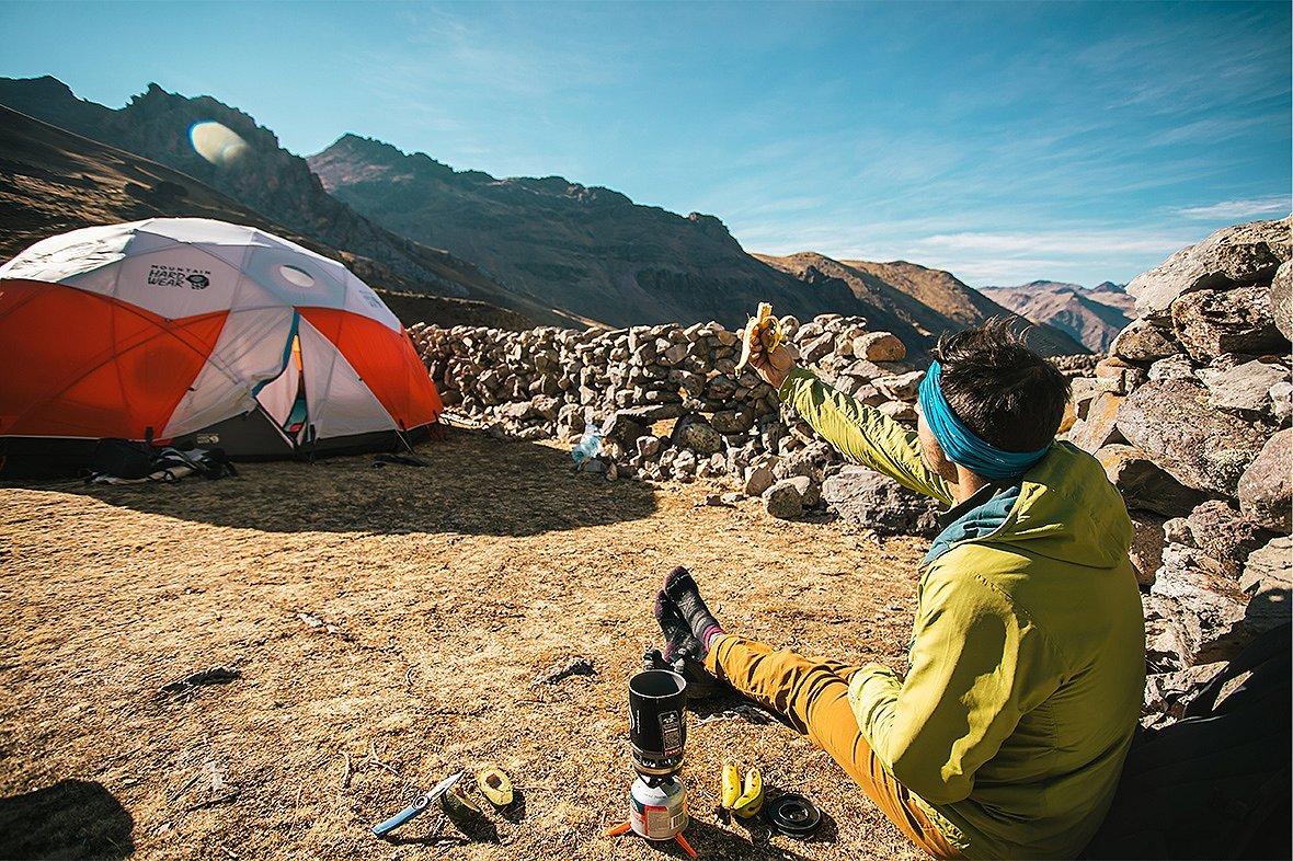 Josh at camp, holds a banana to the sun while admiring the beauty and charm of the Stronghold Dome tent.
