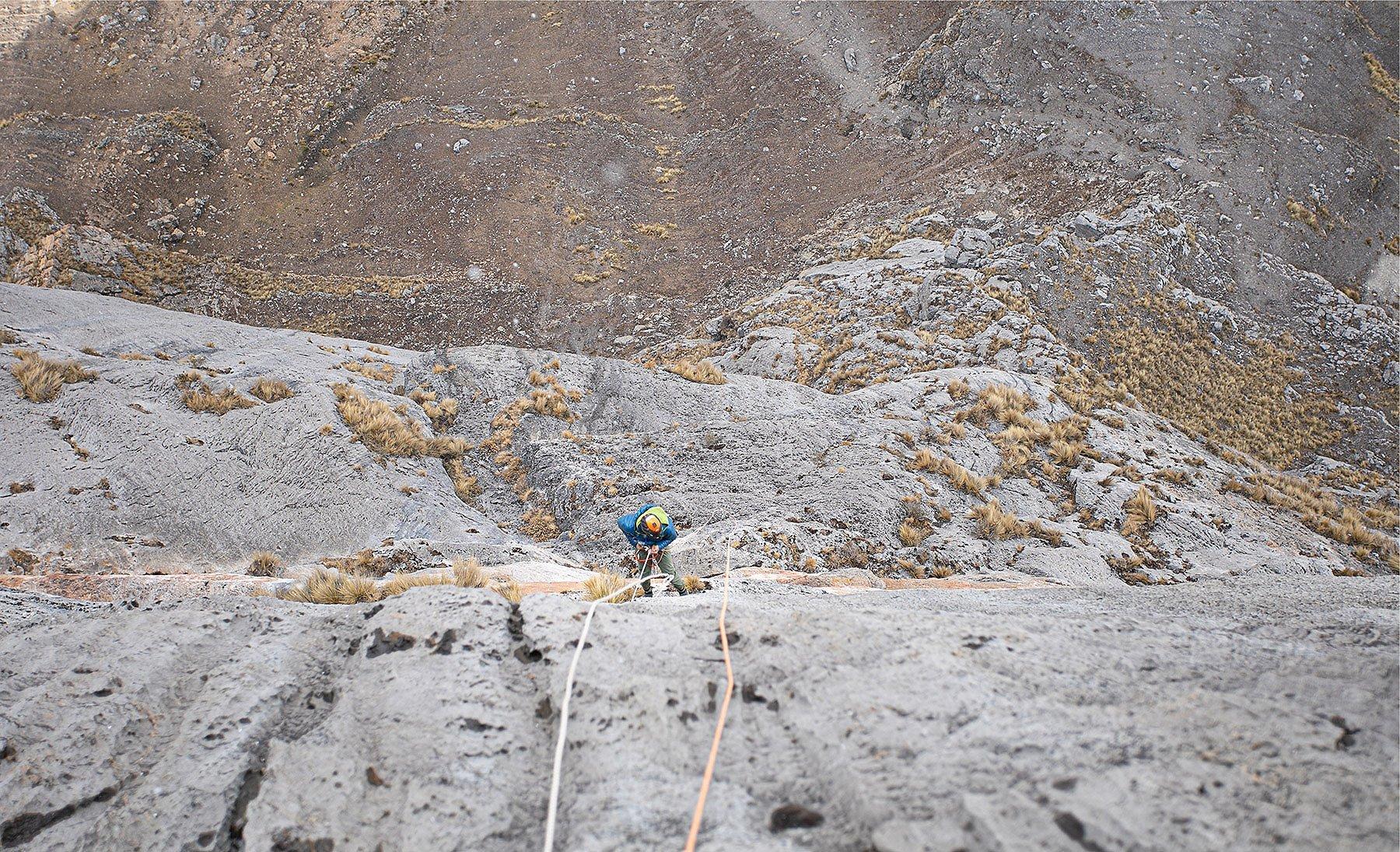 Downward shot of repelling on the wall, investigating the rock to find the best way up.