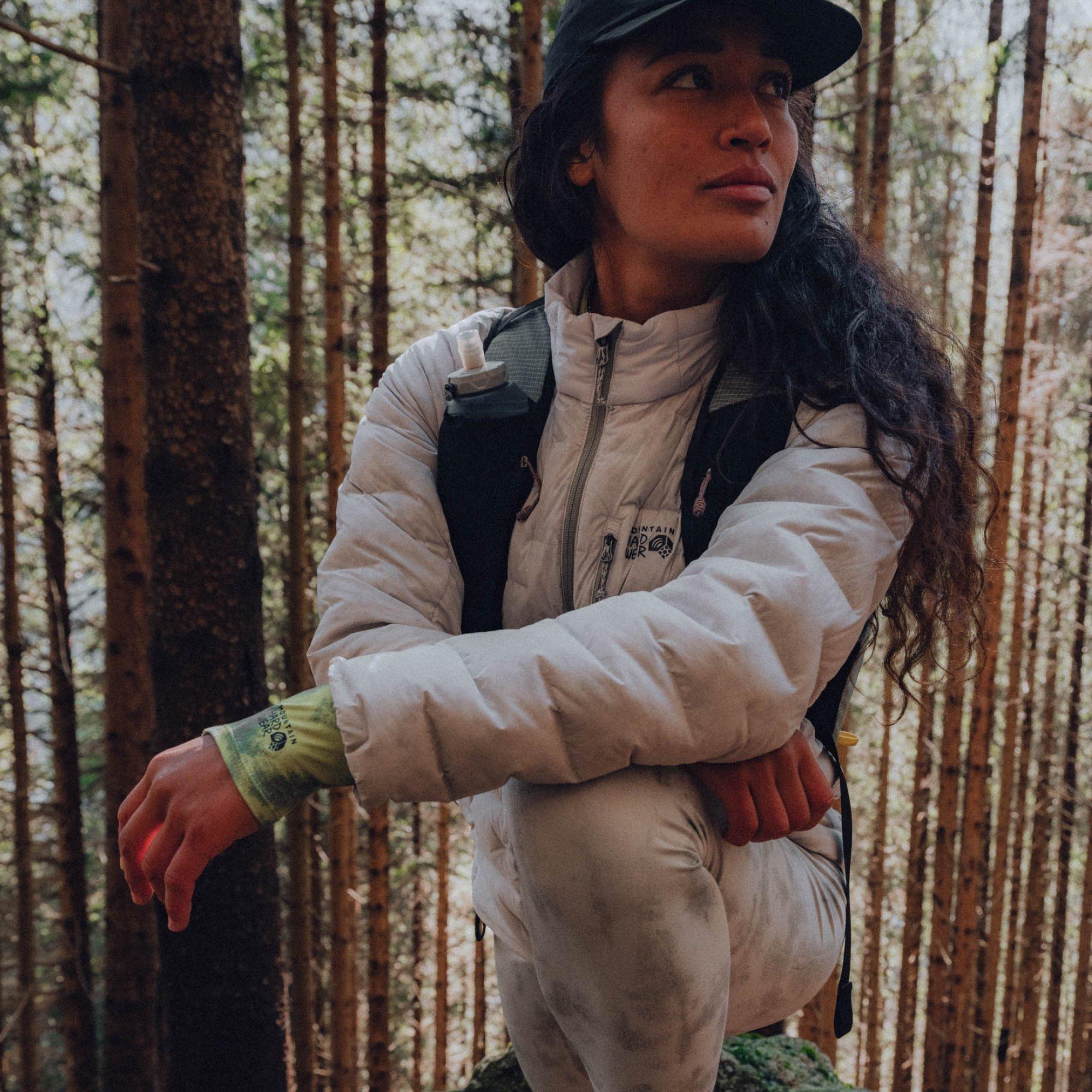 Towering old growth trees behind her, professional ultrarunner Alexa Romano takes a knee, listening.