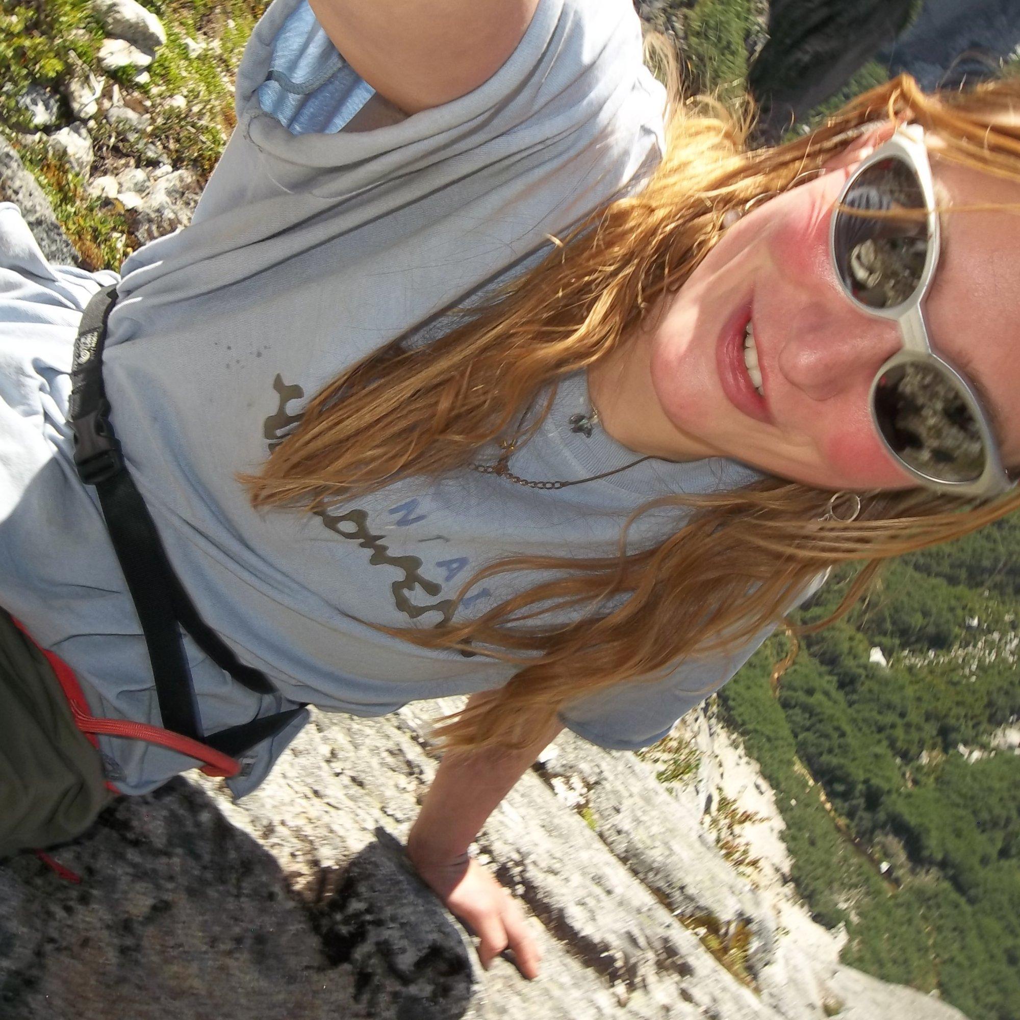 With flushed cheeks and a wry smile, professional climber Flavie Cardinal takes a seated selfie post-ascent.