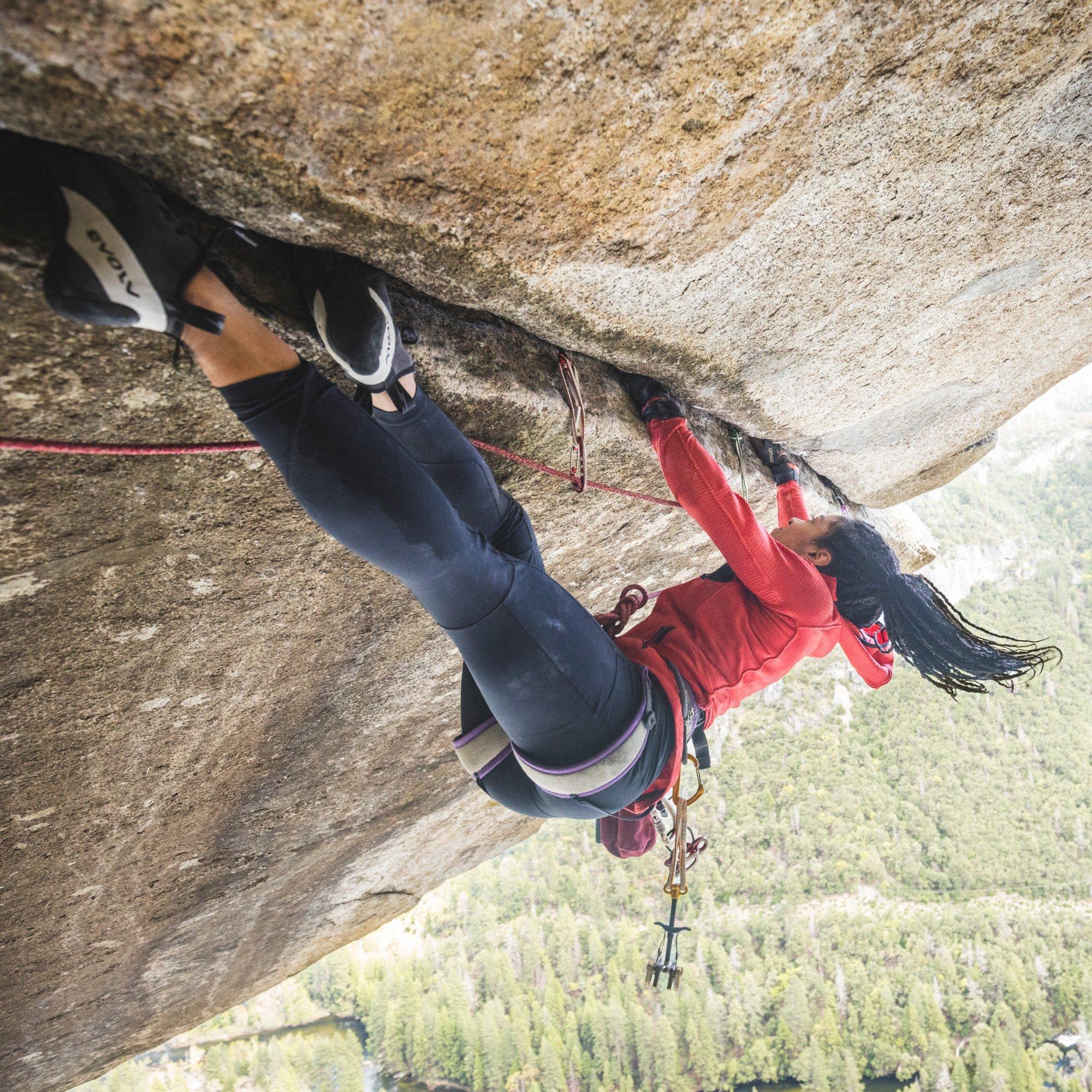 Hanging from fingers and toes, professional climber Genevive Walker jams a horizontal crack along a ledge.