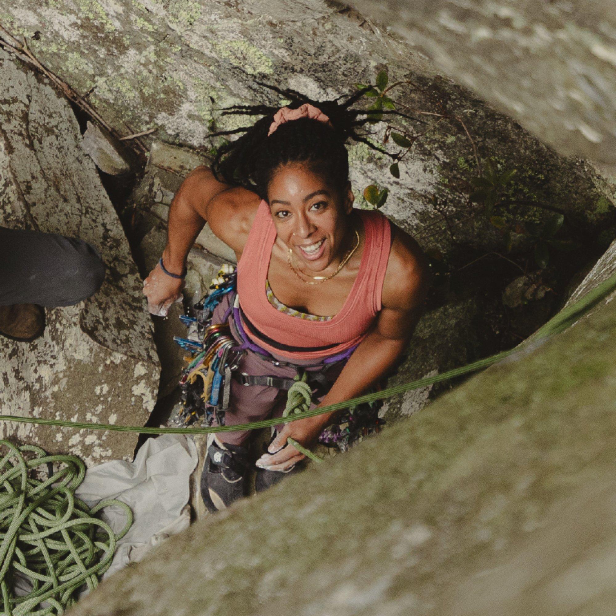 Steadying a freshly tied rope, professional climber Genevive Walker chalks her hands and smiles up at the camera.
