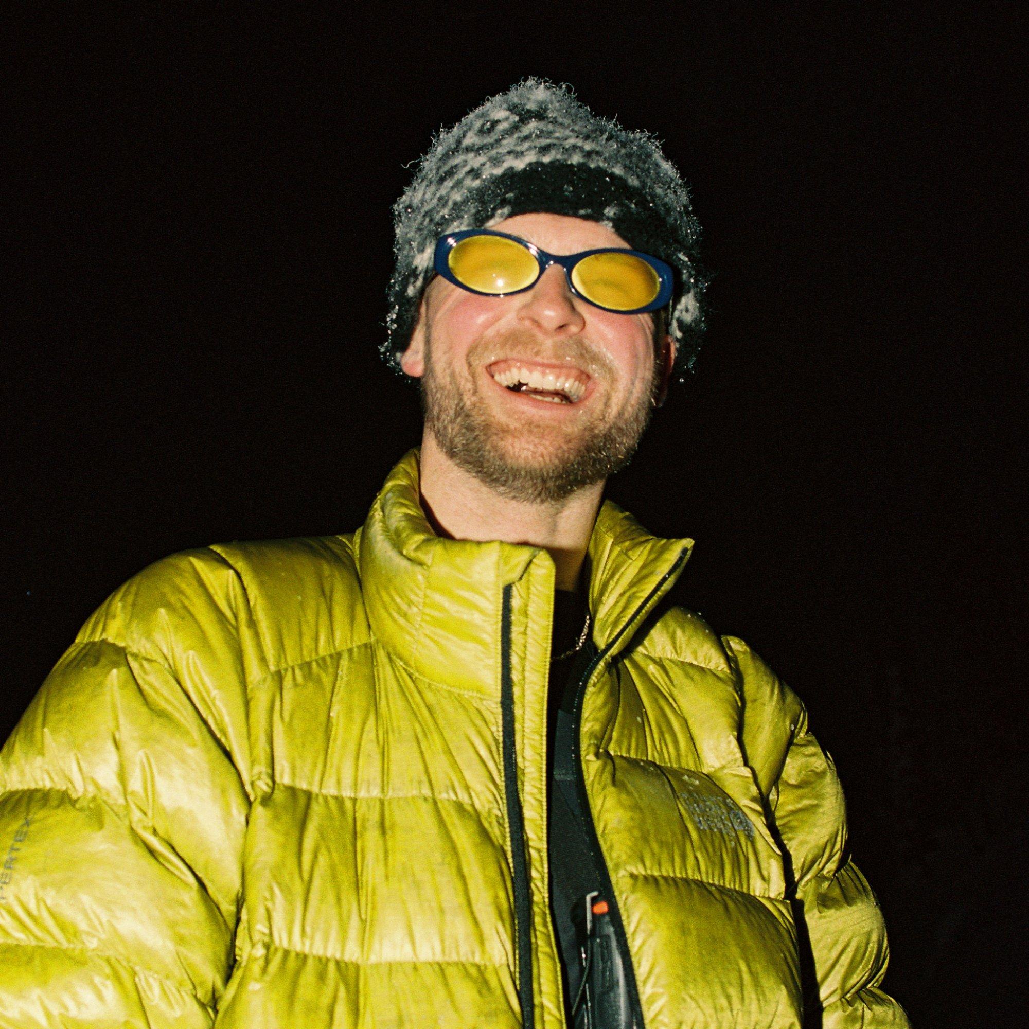 With foggy glasses and a frost-crusted beanie, professional snowboarder Jake Kuzyk is caught laughing candidly.