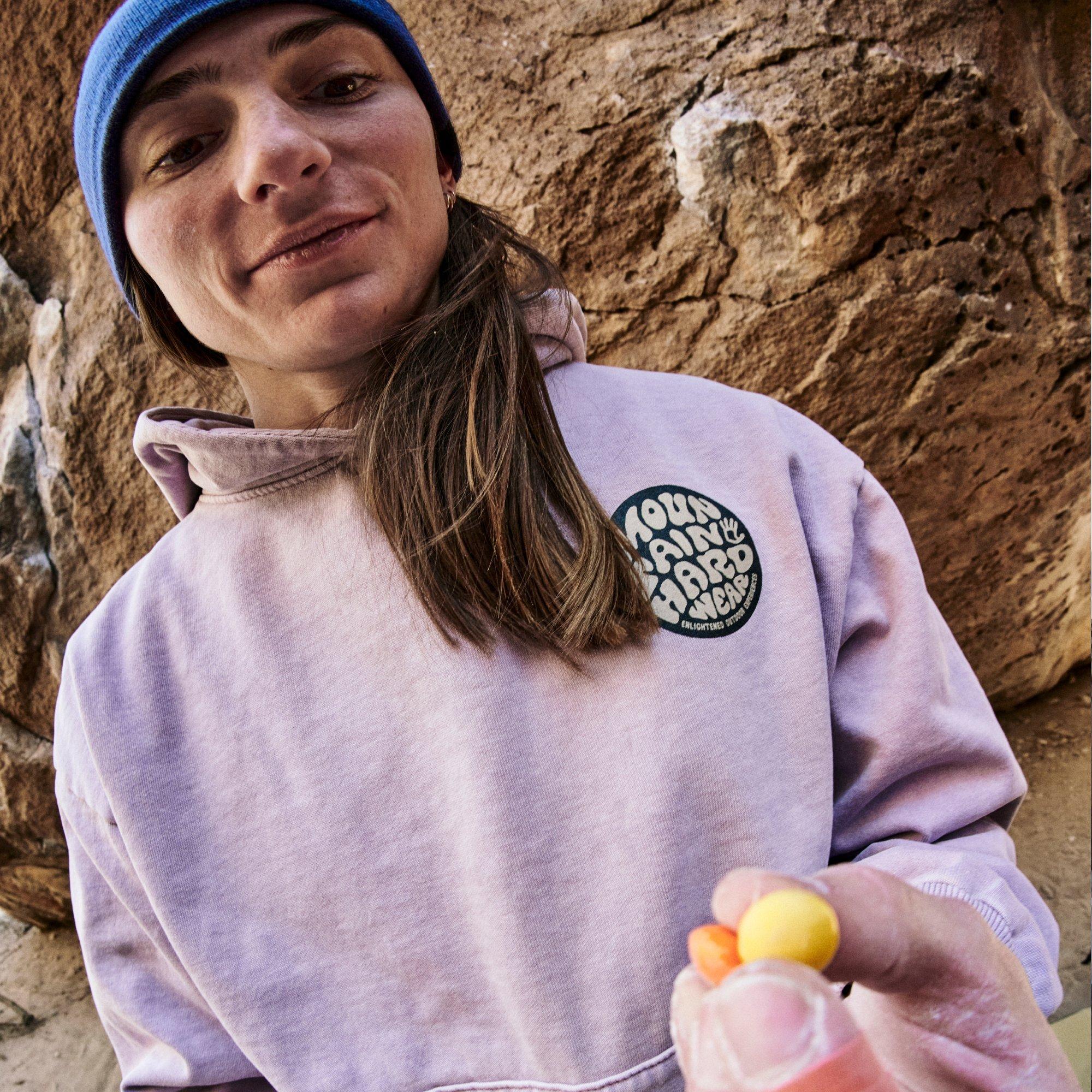 Using heavily taped and chalky fingers, professional climber Kyra Condie offers the viewer pieces of colorful Skittles candy.
