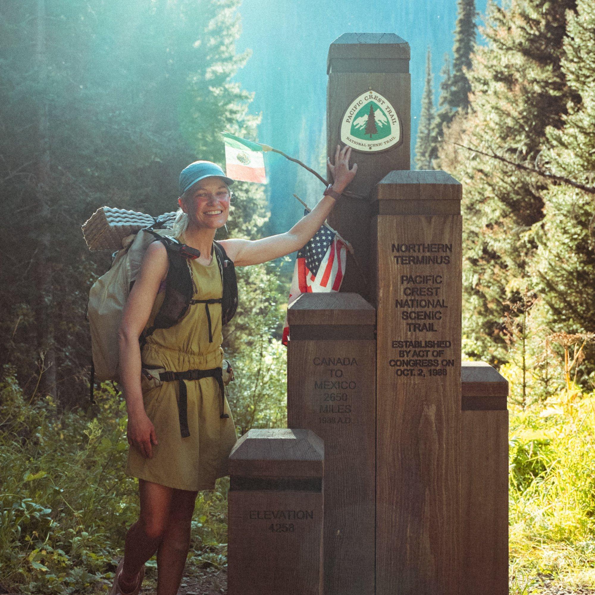 Professional trail athlete Liz Derstine proudly poses next to the Northern Terminus of the pacific Crest Trail.