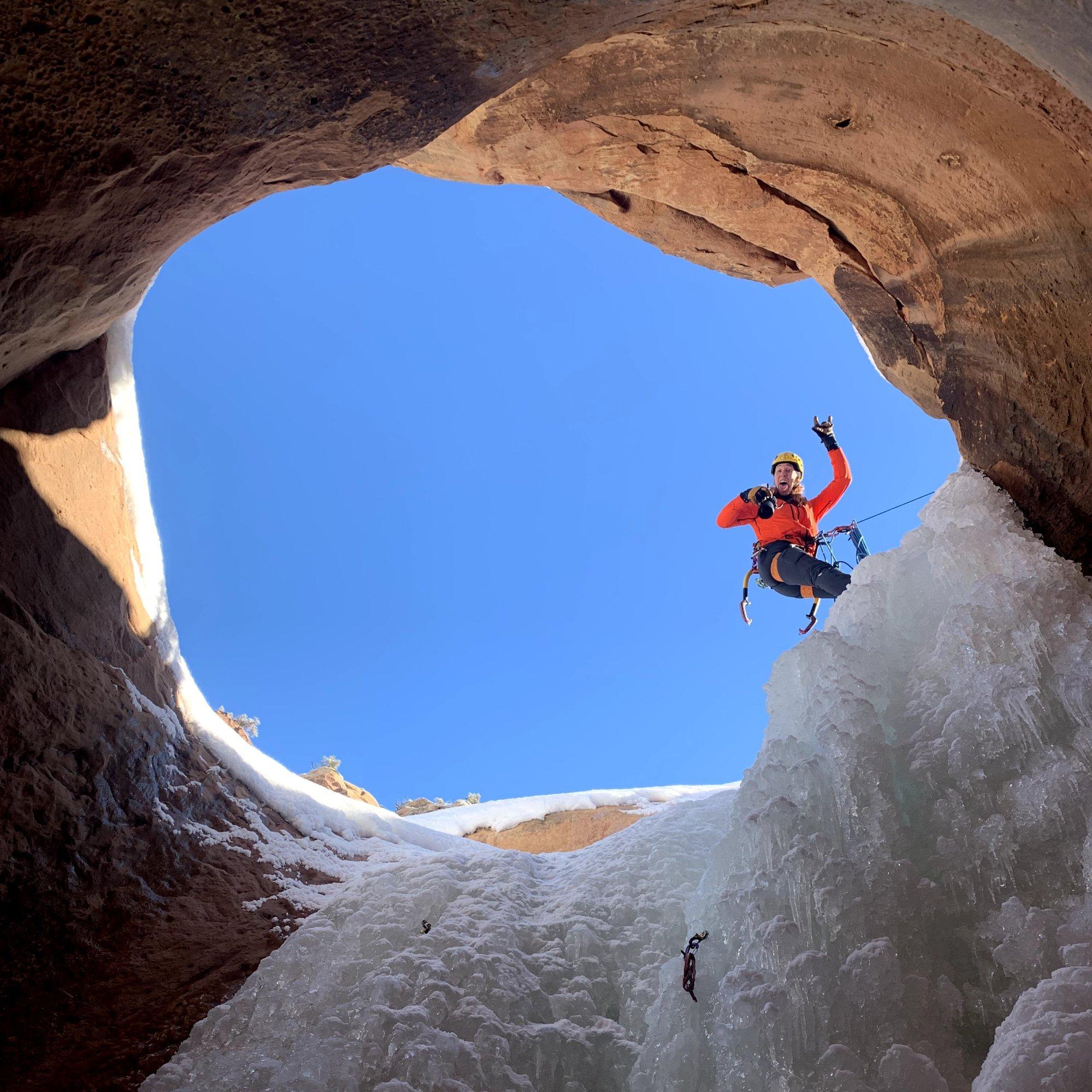 Camera in hand, professional climber and photographer Nikki Smith peers down an ice tunnel, sticking out her tongue and throwing ‘devil horns.’
