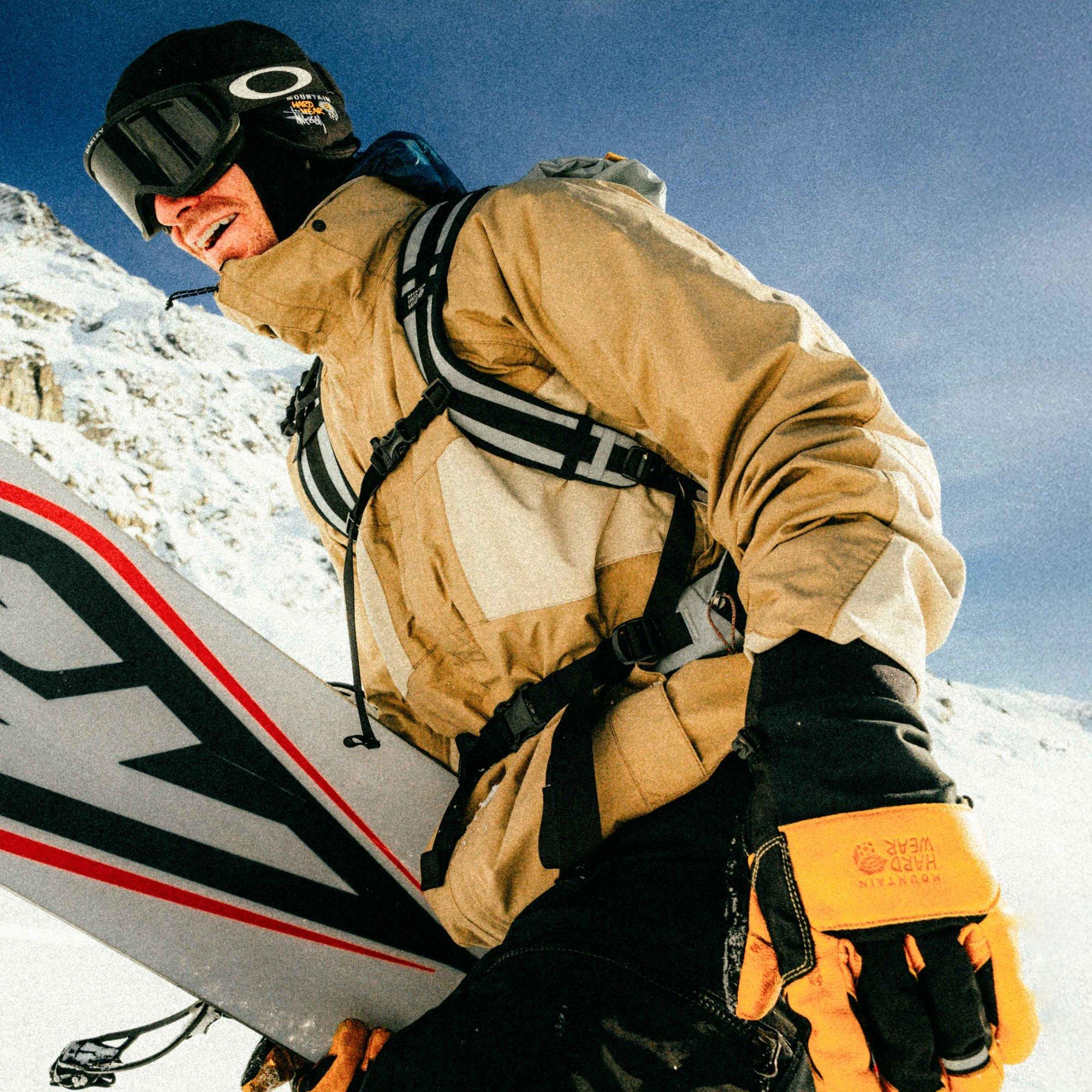 Smiling with stoke post-run, professional skier/snowboarder Sean Petit starts trekking back up the mountain.