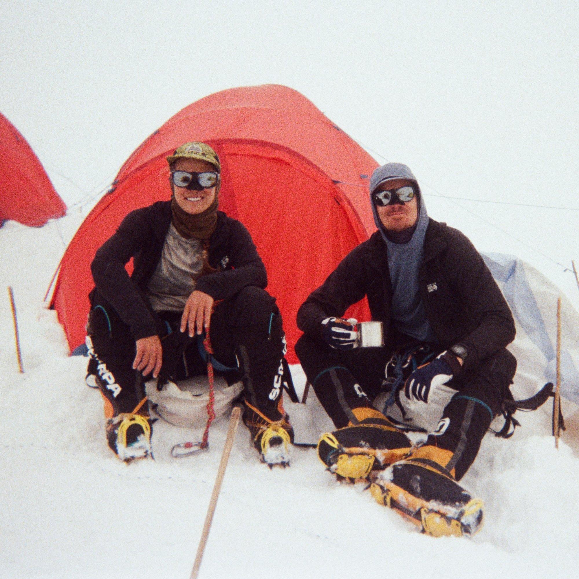 Wearing glacier glasses with nose shields, professional deaf mountaineers Scott Lehmann and Shayna Unger enjoy coffee at camp.